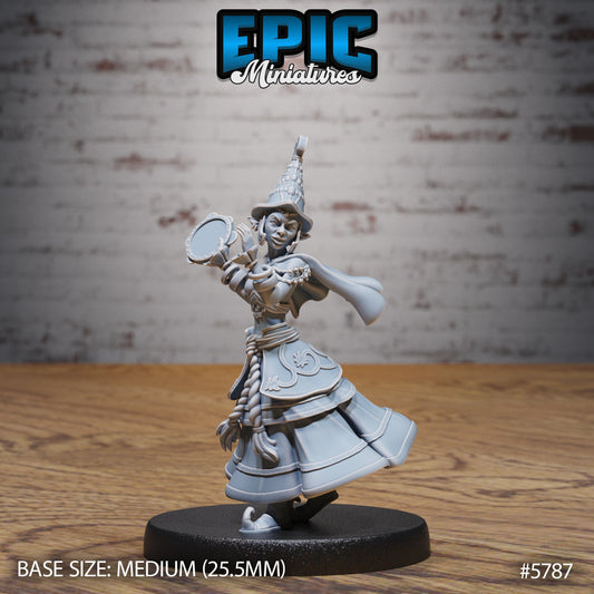 Half-Elf Bard miniature holding a tambourine mid-performance, dressed in layered skirts and ornate armor with braided hair and a pointed hat on a 25.5mm base.
