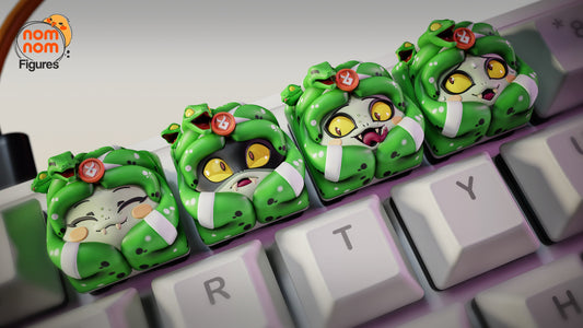 Close-up of four Dusa keycaps on a keyboard, each with a different face expression, featuring snake hair and blush details.