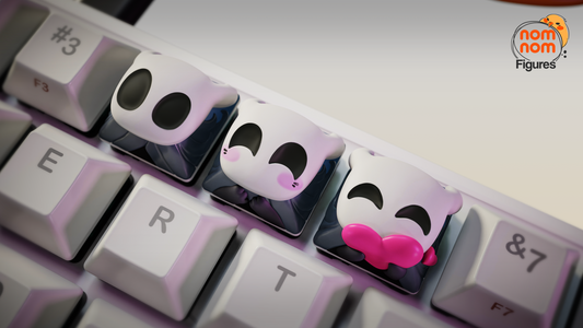Close-up view of Hollow Knight artisan keycaps on a keyboard, displaying cute facial designs including blush and a kiss.