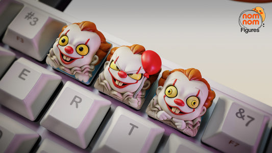 Close-up of IT Clown Halloween keycaps on a mechanical keyboard, featuring three creepy clown faces with grins and yellow eyes – NomNom Figures collectible keycap set.