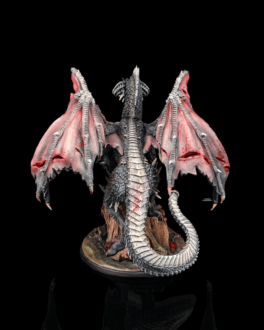 Painted black dragon miniature rear view from Beldrad's Bag of Beasts showing extended wings, segmented tail, spined back, and rocky base, ancient black dragon monster for tabletop roleplaying games