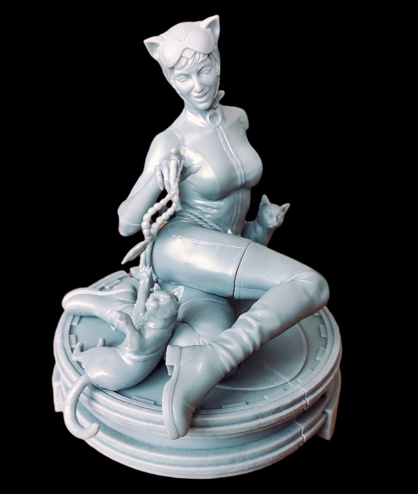 Photo of the assembled Catwoman resin figurine on a tabletop, unpainted gray finish showing suit and cat details clearly.