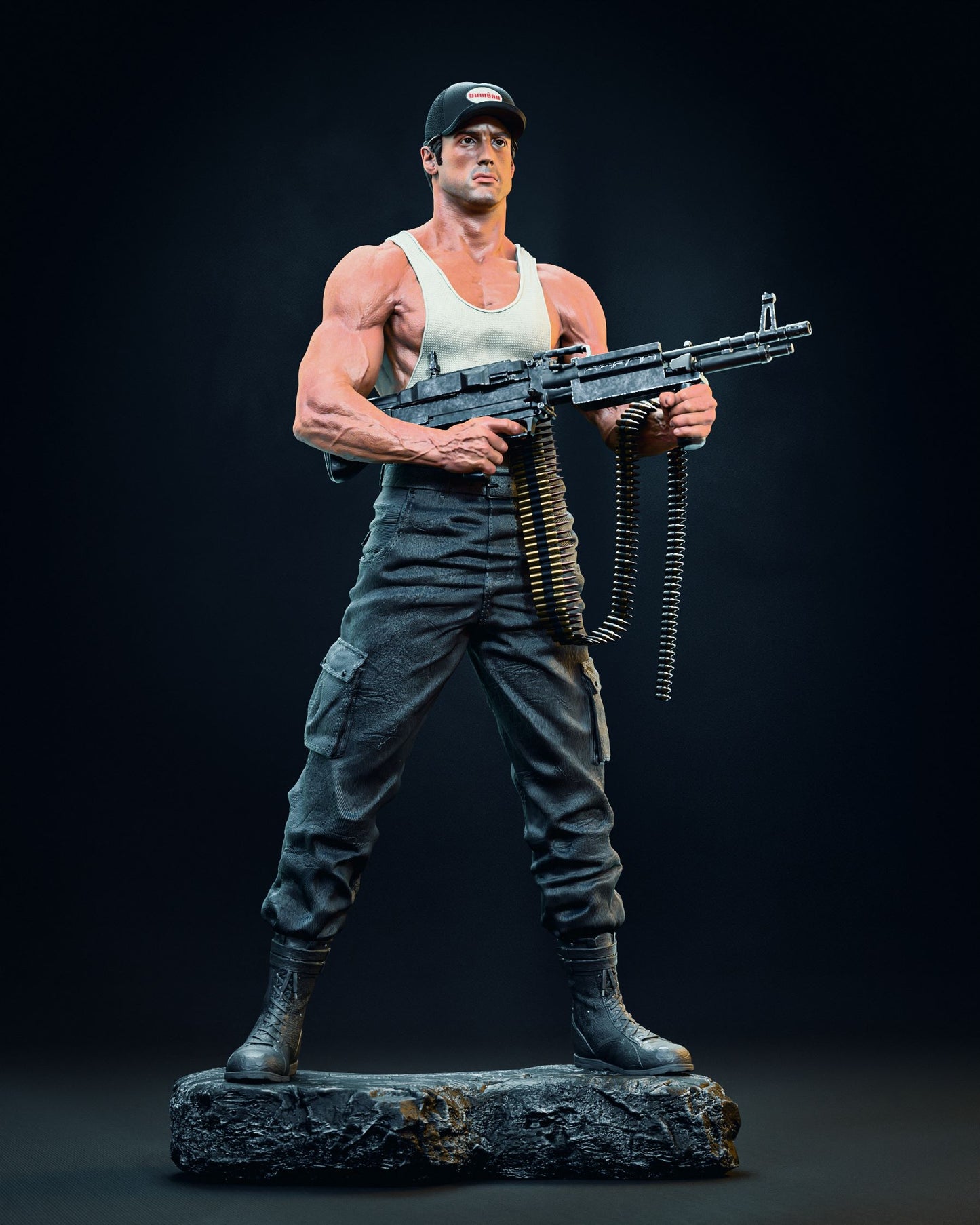 Full-body collectible figurine of Sylvester Stallone as Lincoln Hawk from "Over the Top," in a tank top and cap, holding a machine gun, standing on a rocky base.