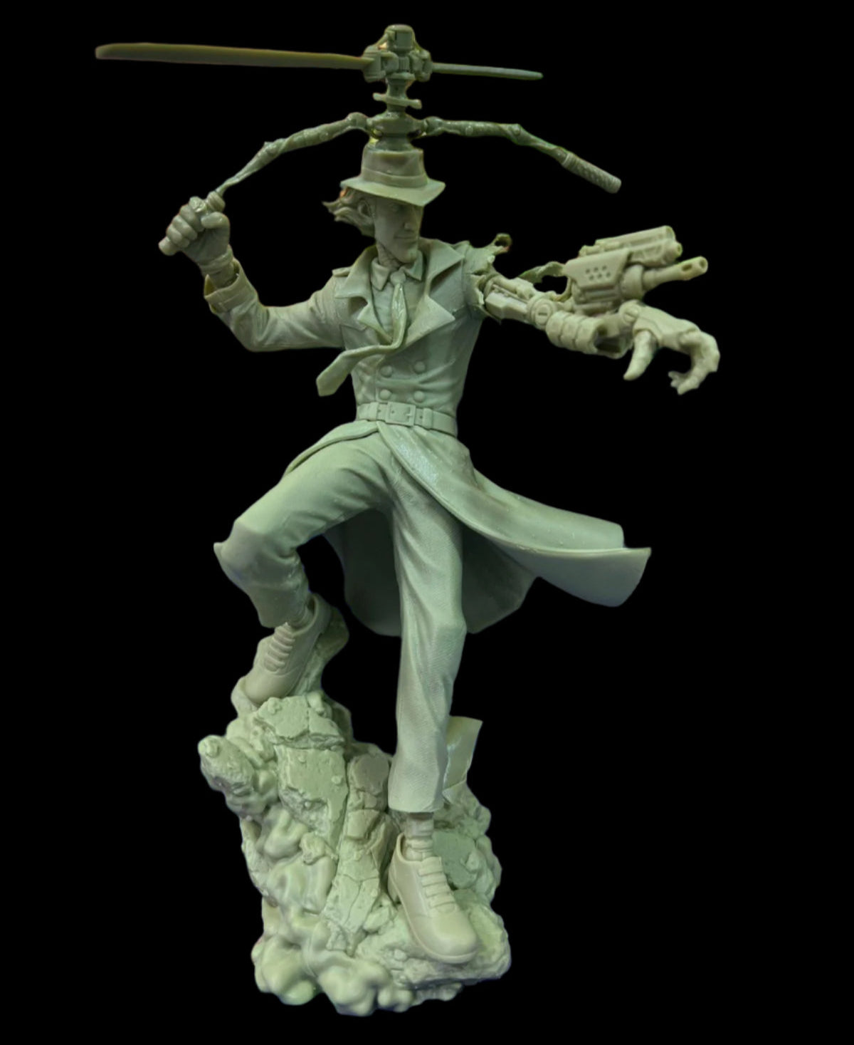 Unpainted raw resin model of Inspector Gadget figure standing on a colorful mat with a fantasy-themed computer wallpaper in the background.