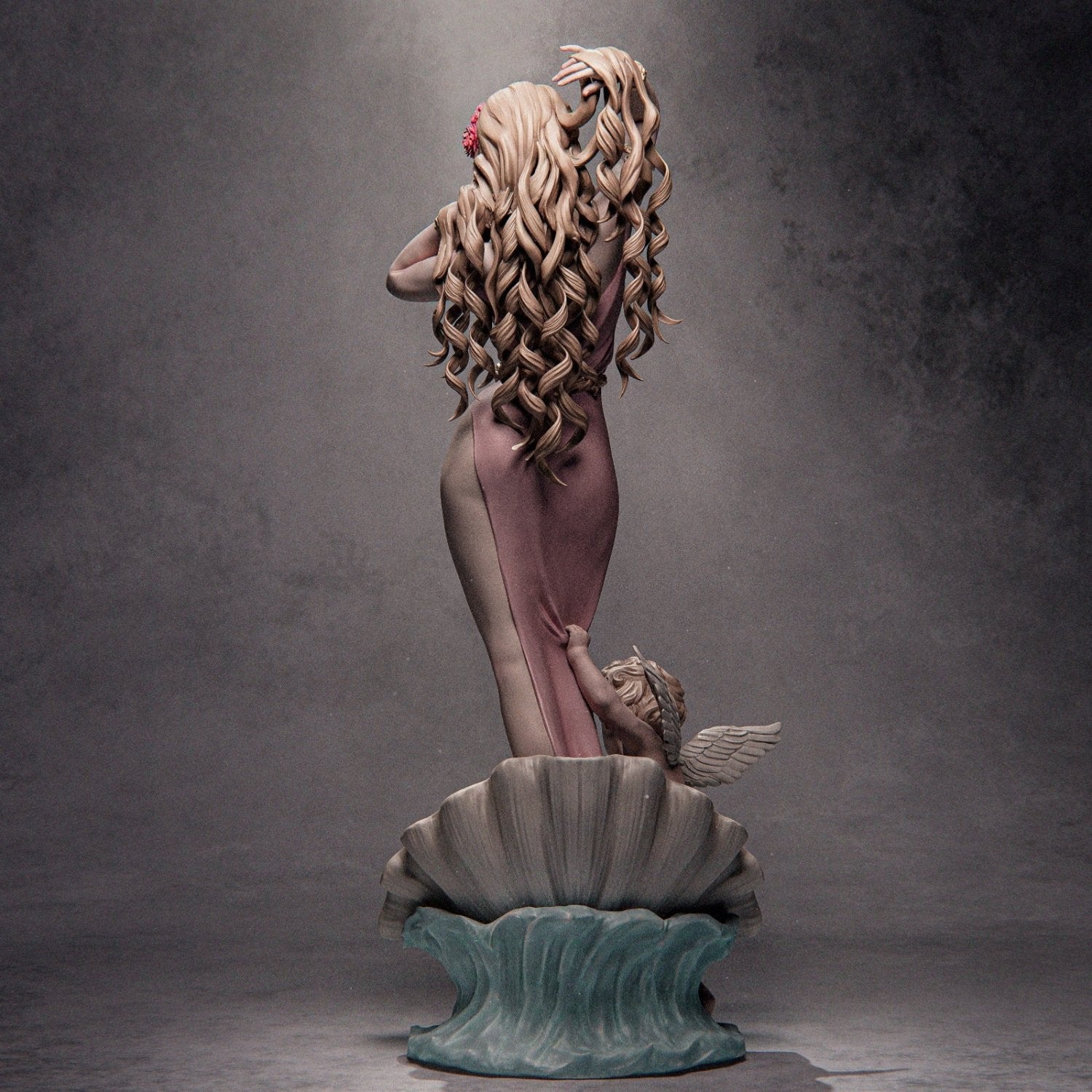 Back view of Aphrodite historical figurine, with long flowing hair and a cherub pulling at the gown while she stands on a seashell.