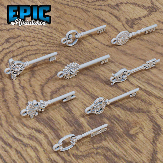 Set of eight 25 mm ornate fantasy keys laid out on wood grain, each with a unique decorative bow and slim shaft—ideal as dungeon props or treasure accessories.