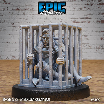 Prisoner cage miniature showing a captive seated inside iron bars with a defeated expression, ideal for Warhammer or DnD campaigns.