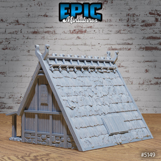 Rear view of Viking House miniature with thatched roofing, side window shutter, and timber siding over a stone base.