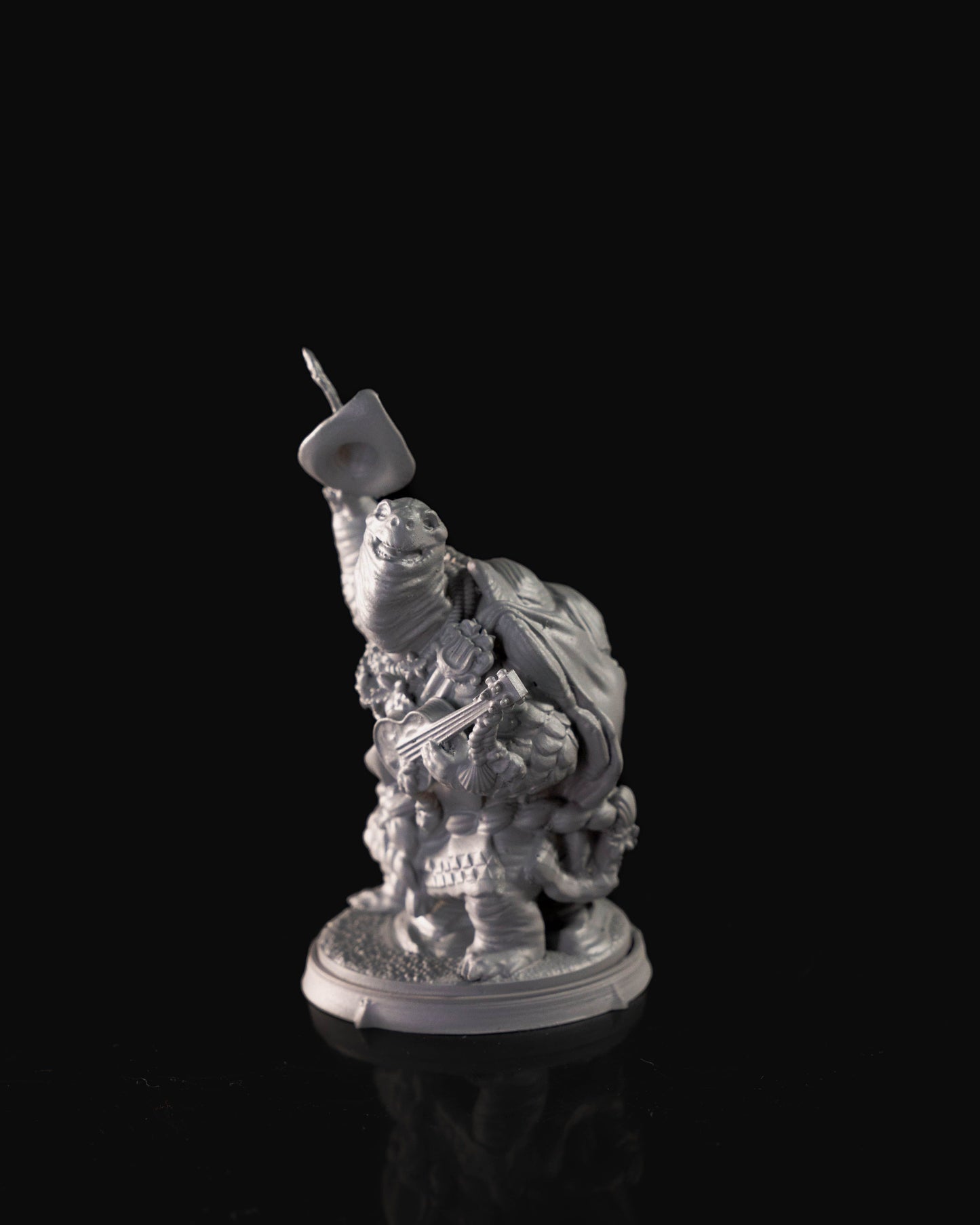 A tortle bard miniature with a large, textured shell and detailed bardic attire, holding a lute in one hand and raising a wide-brimmed hat in the other. The figure is richly detailed with layered clothing and accessories. The base has a patterned design, enhancing the character's whimsical appearance.