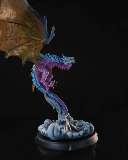 A dragon miniature in flight with vibrant purple and blue scales, positioned over a swirling cloud base.