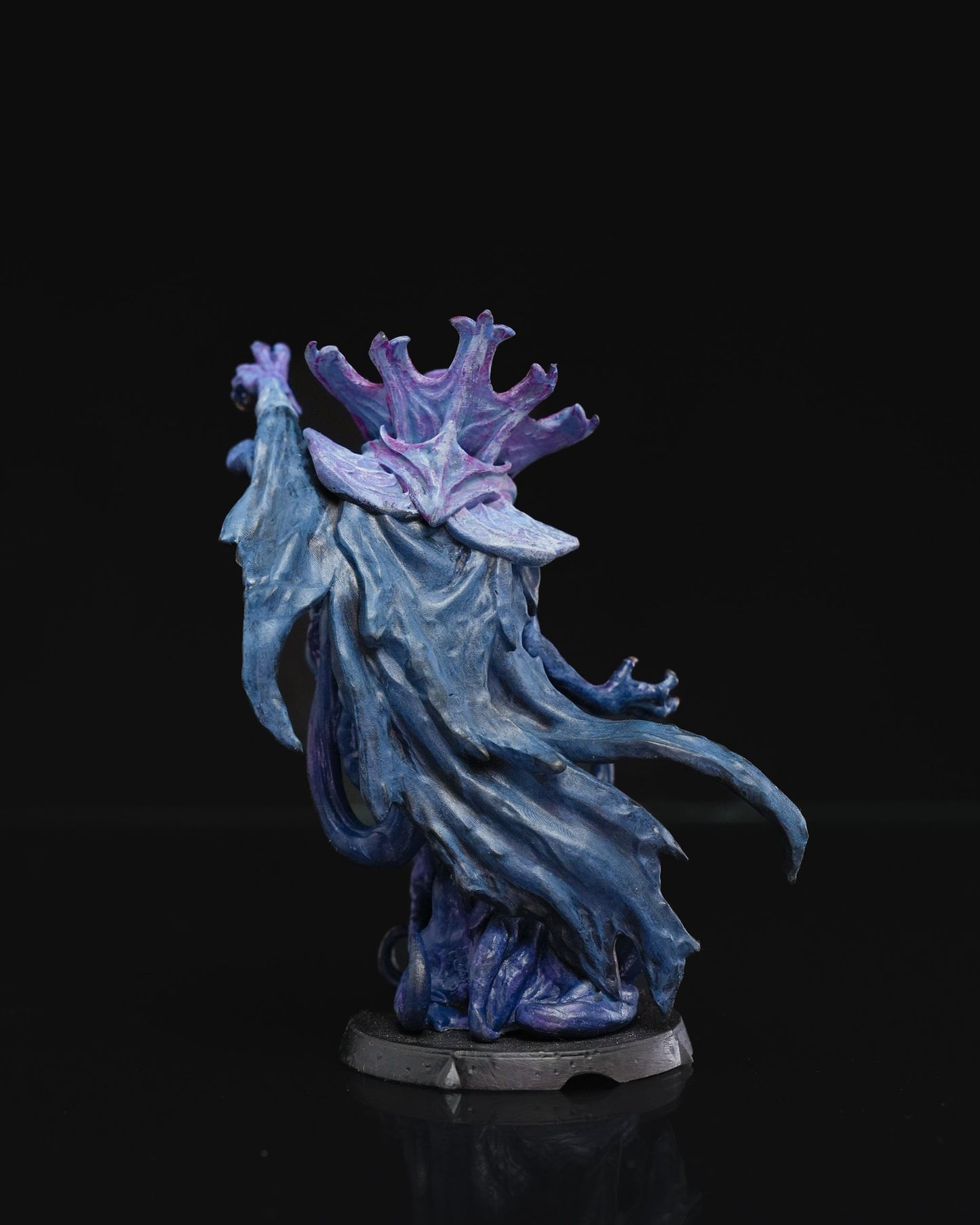 Rear view of a painted mind flayer miniature with flowing blue robes and intricate purple head tentacles, emphasizing the sculpt's texture and dynamic movement.