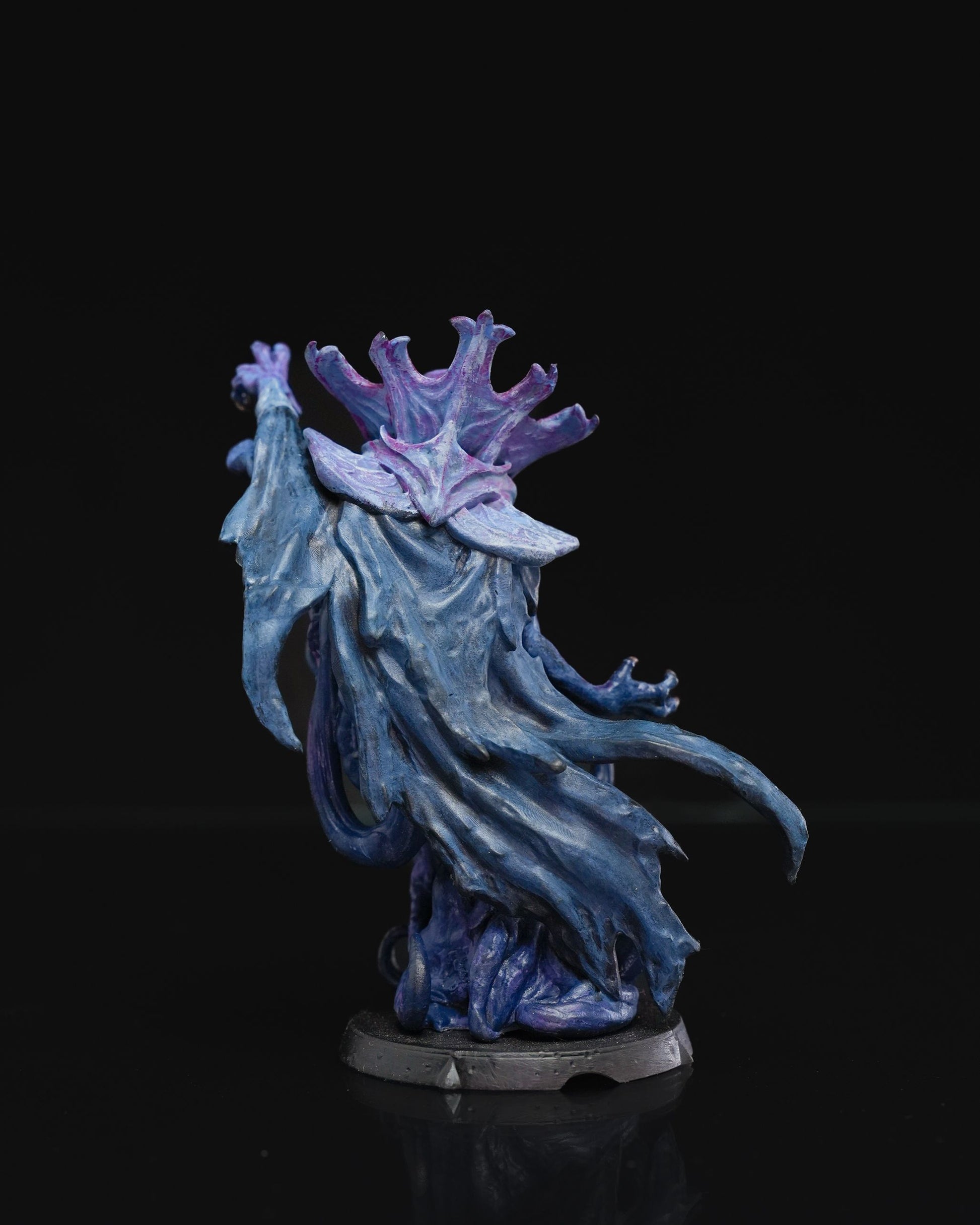 Rear view of a painted mind flayer miniature with flowing blue robes and intricate purple head tentacles, emphasizing the sculpt's texture and dynamic movement.