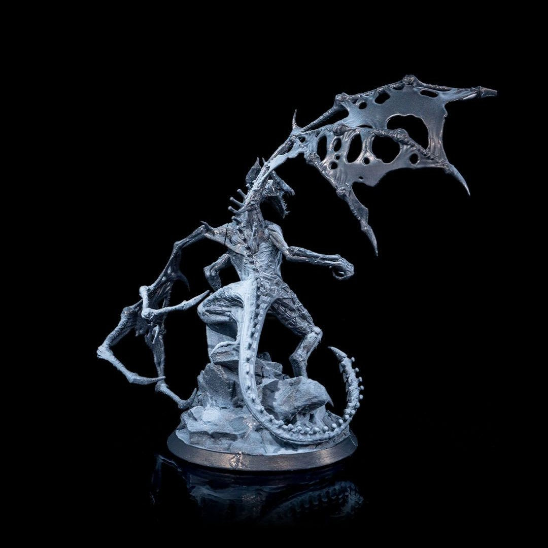 Back view of the Dracolich miniature, showcasing its bony tail, skeletal wings, and detailed rocky terrain beneath its feet.