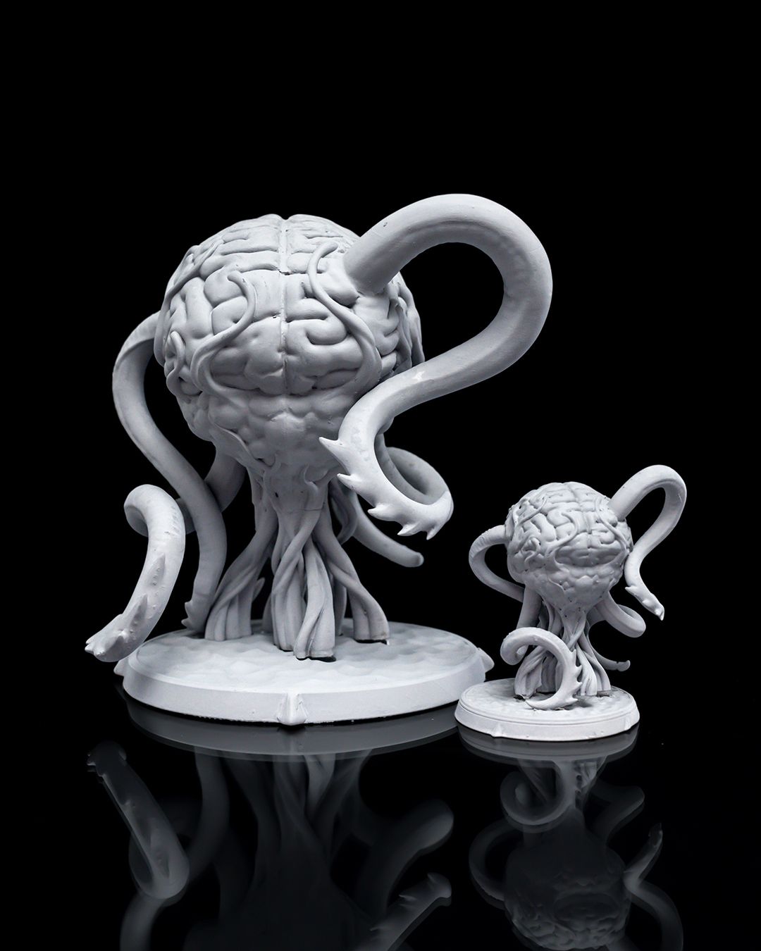 Elder Brains miniatures depicting large, brain-like creatures with writhing tentacles and intricate brain textures, set on circular bases, showcasing both a large and a smaller version of the creature.