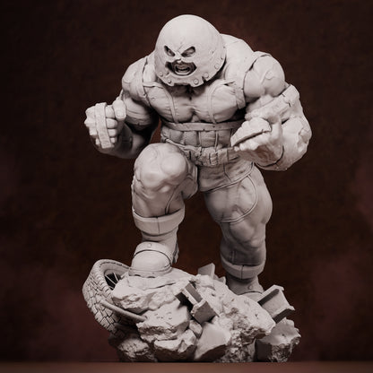 Front view of unpainted Juggernaut collectible figure in mid-stride atop rubble and tire debris, fists clenched and helmeted head snarling forward.