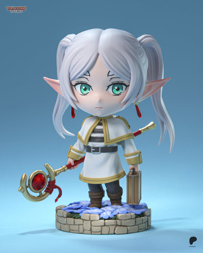 Front view of chibi Frieren figure standing with staff, lantern, and twin ponytails on a flower-covered stone base.