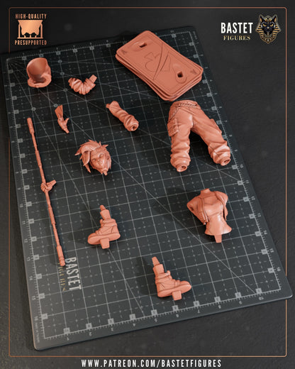 Female Gambit 1:8 figure unassembled parts layout on cutting mat, including head, arms, jacket, pants, staff, boots, and card-stack base components.