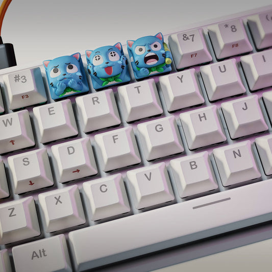 Wide view of three Fairy Tail Happy keycaps installed on a white mechanical keyboard, showing Shy, Cheerful, and Angry expressions in a row, with the NomNom Figures logo visible in the corner.