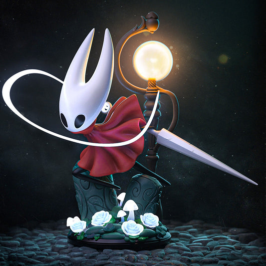 Chibi Hornet figure striking an action pose with her needle weapon extended beside a glowing lamppost, surrounded by roses and mushrooms on a cobblestone base.