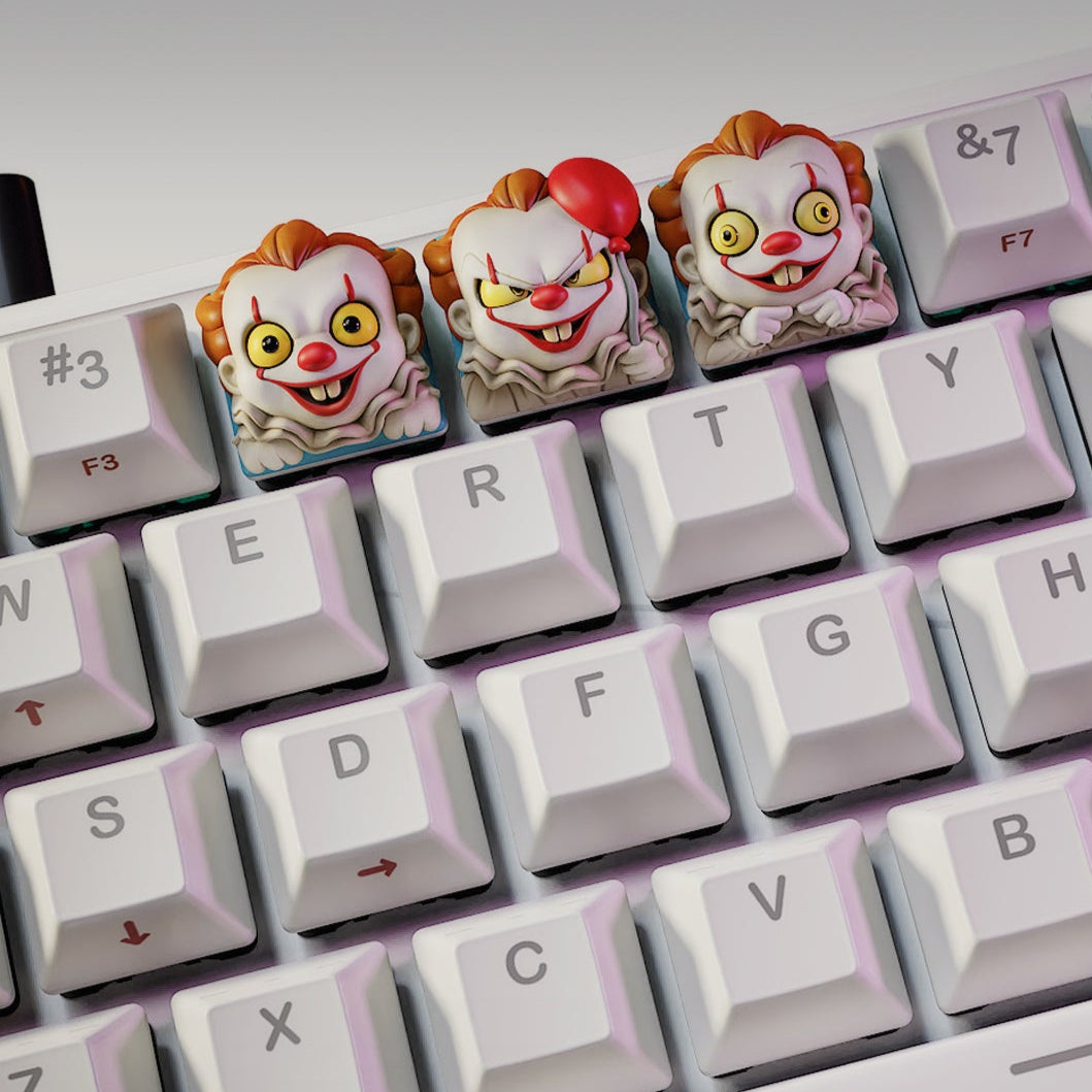 Trio of IT Clown keycaps on mechanical keyboard, one holding a red balloon, inspired by horror clowns – NomNom Figures Halloween collection.