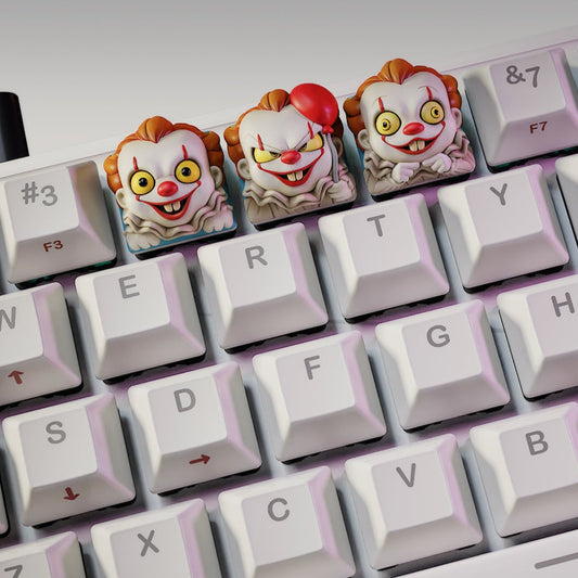 Trio of IT Clown keycaps on mechanical keyboard, one holding a red balloon, inspired by horror clowns – NomNom Figures Halloween collection.