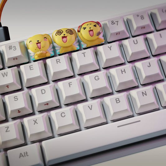 Wide keyboard view displaying the full trio of Card Captor Sakura Keroberos keycaps by NomNom Figures, highlighting the detailed wings, bright yellow color, and whimsical poses.