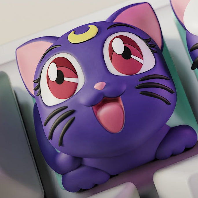 Close-up of the Happy Luna keycap from Sailor Moon, featuring a purple cat with bright red eyes, an open mouth smile, and a crescent moon on her forehead.
