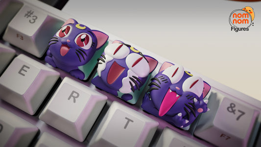 Close-up of Luna keycaps from Sailor Moon on a mechanical keyboard, showing three expressions—Happy, Laughing with tears, and Mischievous grin—with the NomNom Figures logo in the corner.