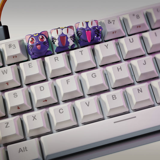 Angled view of the Luna Sailor Moon keycaps installed on a white mechanical keyboard, highlighting the detailed sculpting and colorful expressions of the three lunar cat designs.