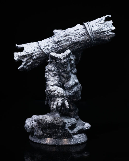 A miniature of Orthos the Troll carrying a large log over his shoulder, standing on a rocky base, with a rough, stone-like texture on his skin.