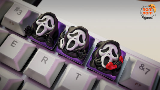 Close-up of Ghostface keycaps on keyboard, one holding a knife, another with a phone, and one mid-scream – NomNom Figures Halloween collection.