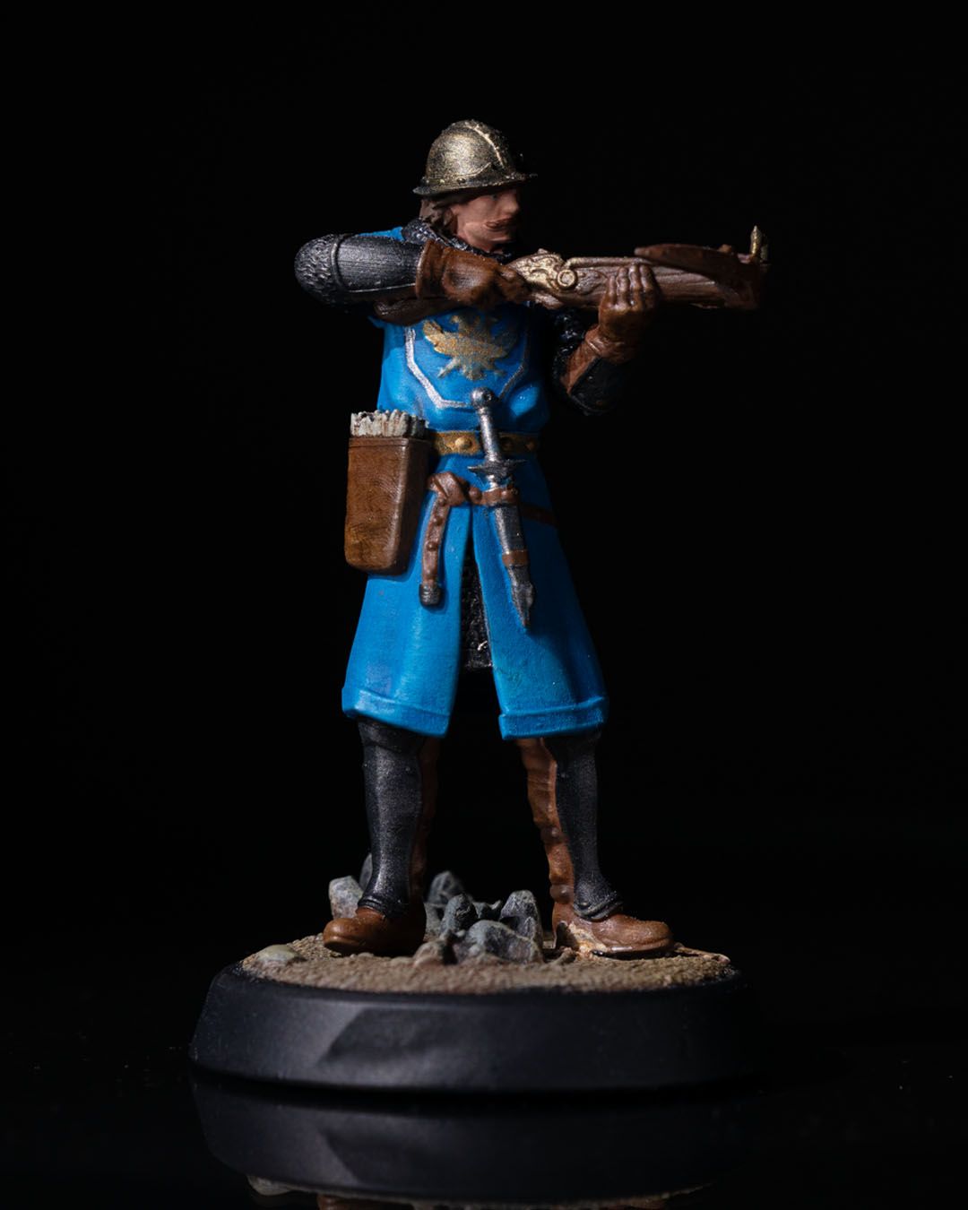 Painted miniature of a Town Guard aiming a crossbow, wearing a blue tunic with chainmail and a helmet.