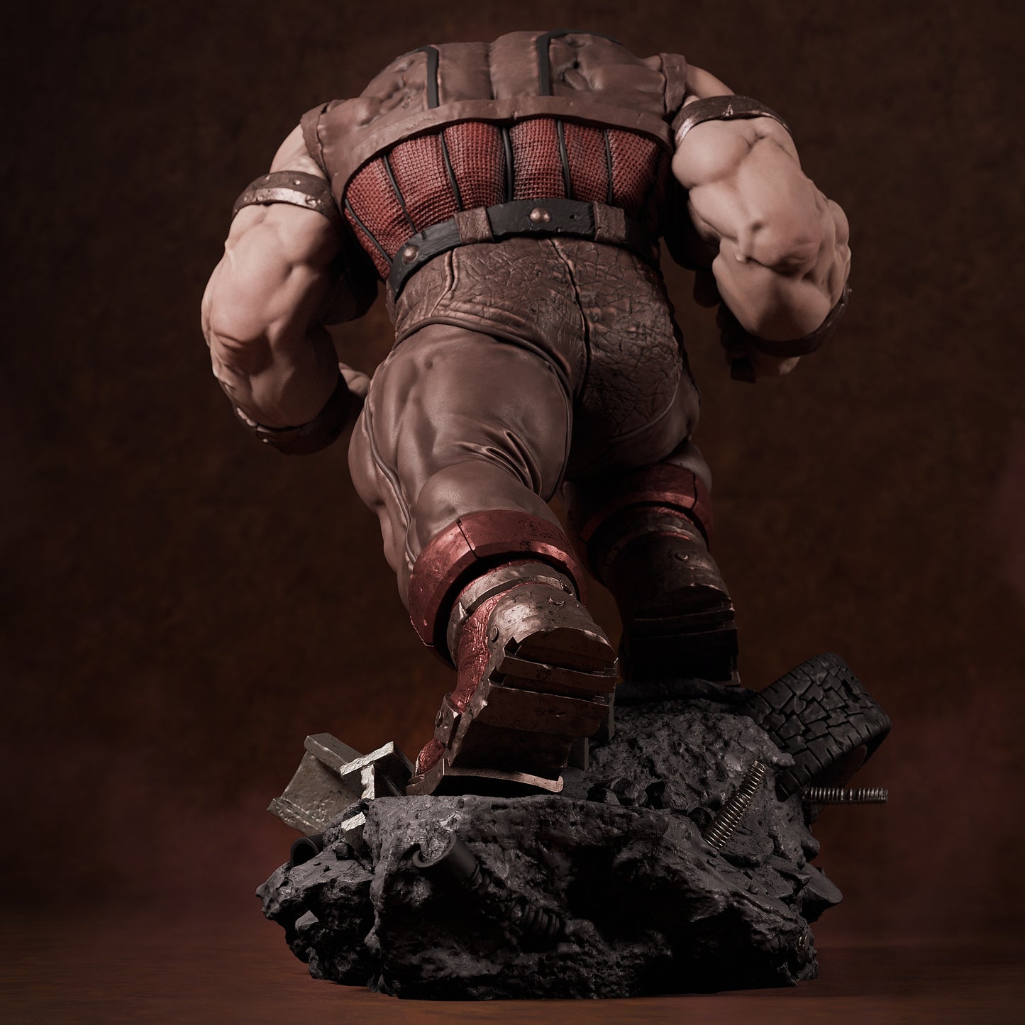 Rear view of painted Juggernaut collectible showing muscular back, leather textures, and rock base with crushed tire and bolts.