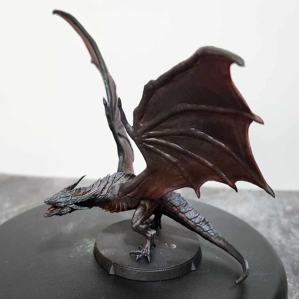 A painted dragon miniature with outstretched wings, detailed with dark scales.