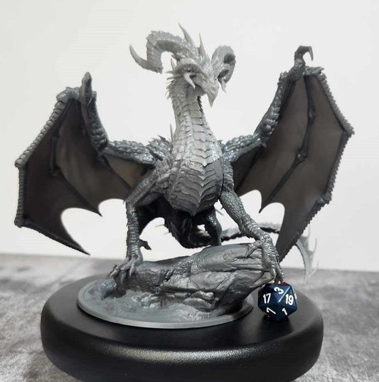 A highly detailed miniature of an Elder Black Dragon, showcasing its menacing posture with wings spread wide, sharp claws gripping a rocky base, and a spiked crest on its head. The dragon exudes a sense of ancient power and dominance, ready to strike fear into its enemies.