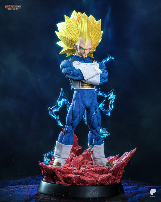 Front view of SSJ3 Vegeta figure standing on rocky red base, arms crossed over chest, golden spiked hair, blue energy effects surrounding figure.