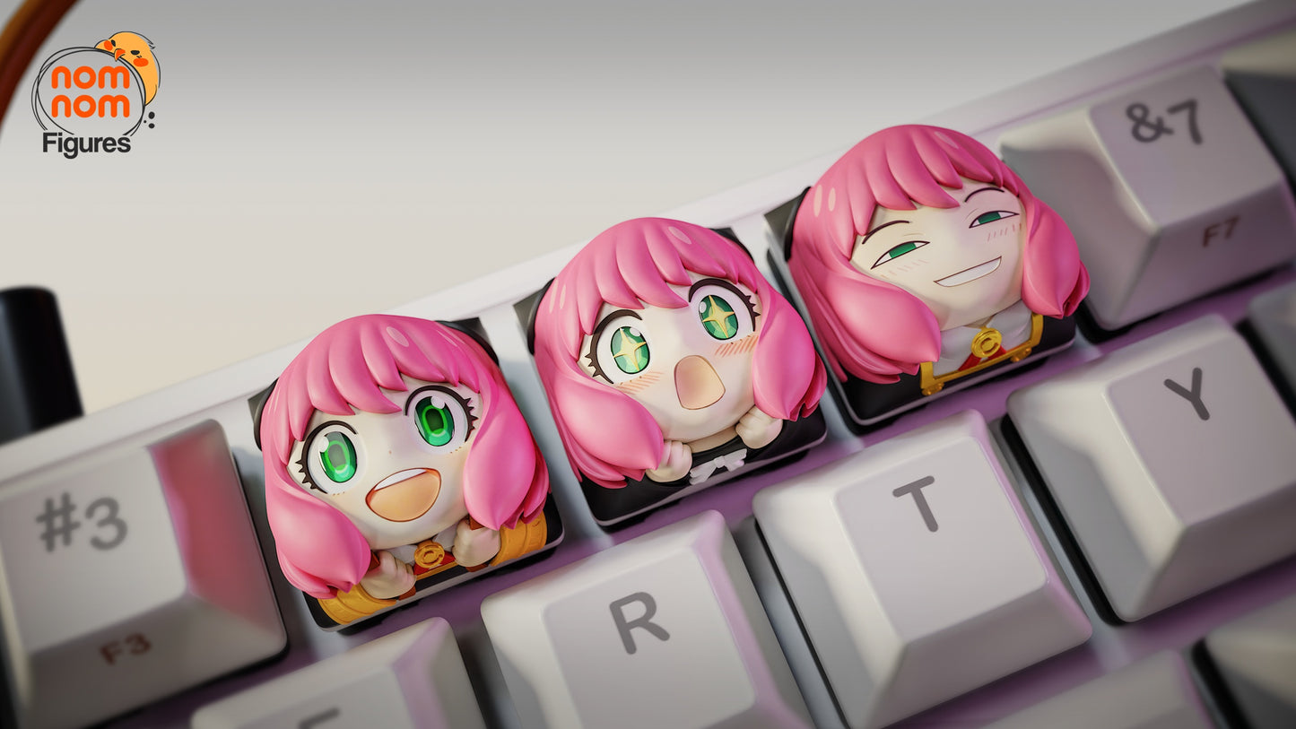 Top-down view of three Anya keycaps with excited, shocked, and sly chibi expressions placed across the E, R, and T keys, adding an anime-inspired playful touch to the keyboard.