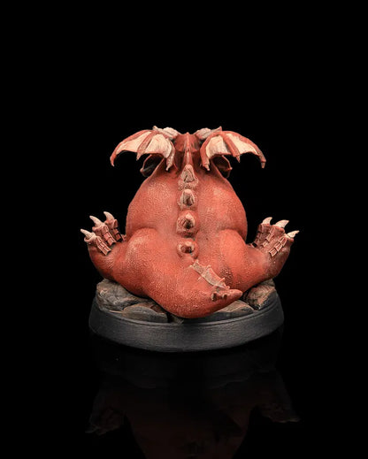 Young red dragon creature miniature rear view from Beldrad's Bag of Beasts showing rounded tail, folded wings, thick scales, and comically bulky dragon anatomy for tabletop roleplaying games