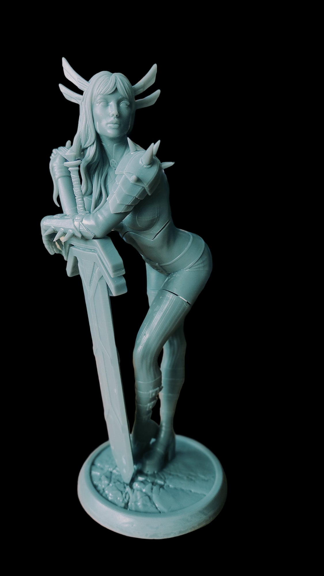 Front view of unpainted Magik figure, posed with one hand holding a large sword and the other resting on her hair, spiked shoulder armor visible.