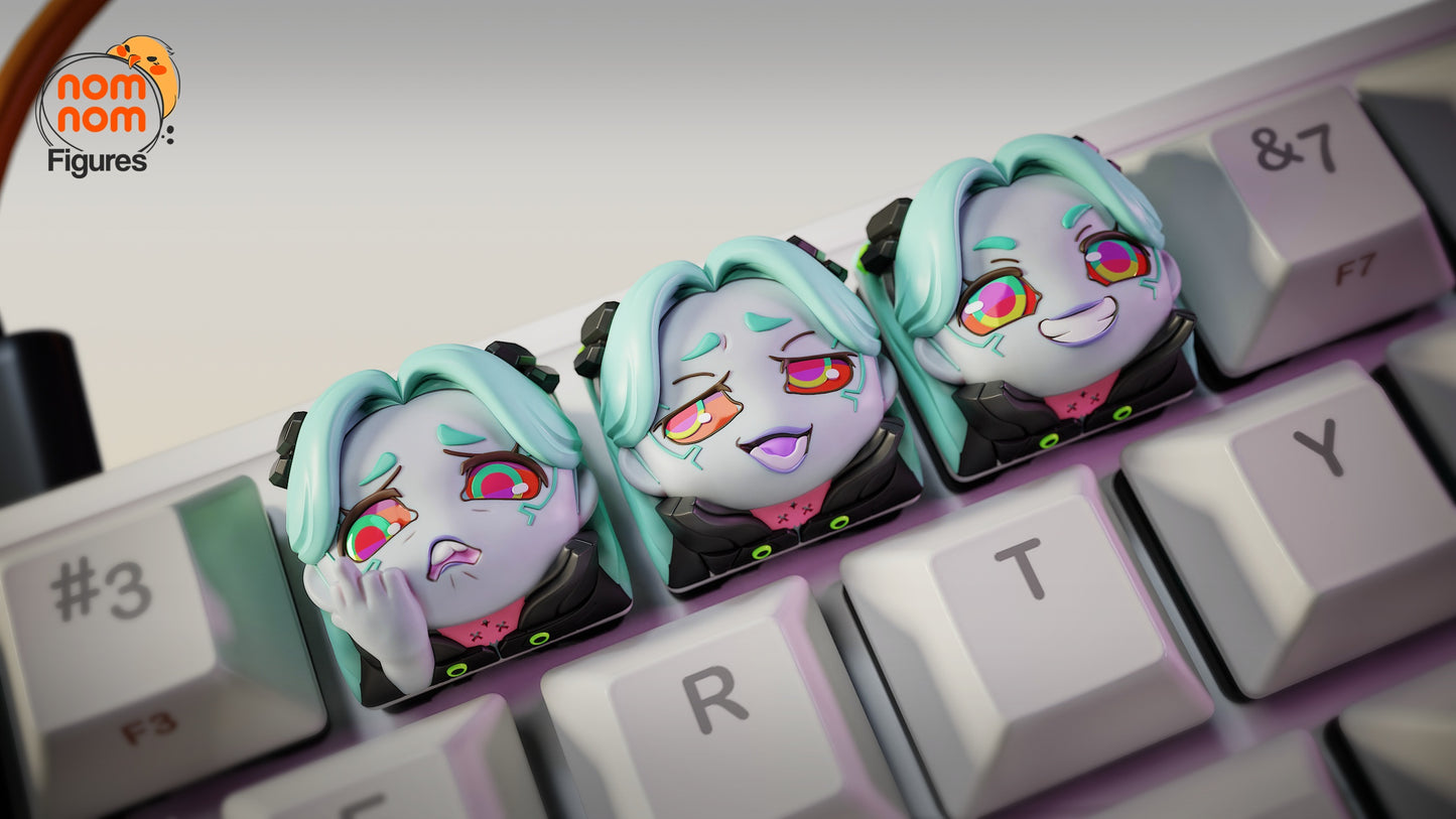 Close-up of three custom Rebecca keycaps from Cyberpunk: Edgerunners on a keyboard, showing sad, smug, and maniacal expressions.
