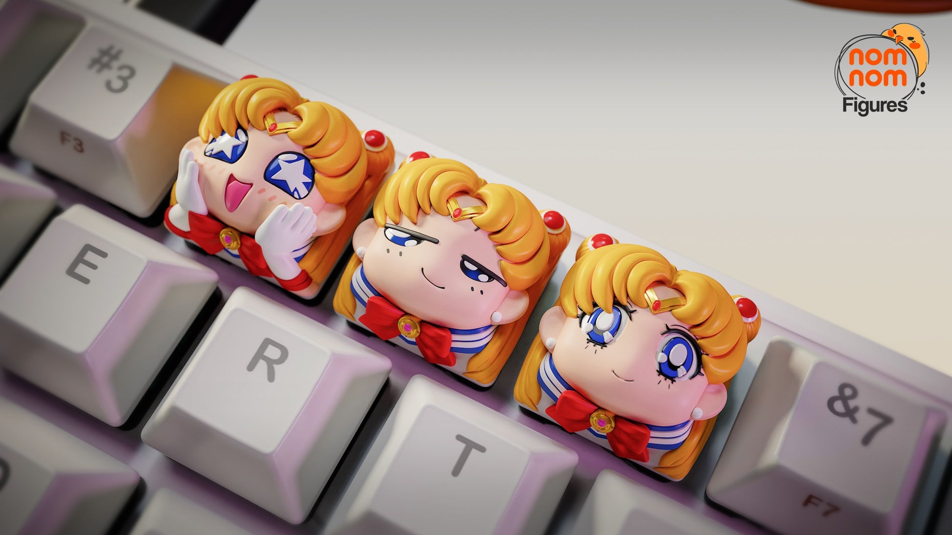 Close-up of three Sailor Moon artisan keycaps on a keyboard, showing her excited, smug, and smiling faces.