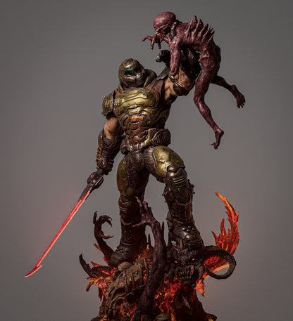 Full-figure front view of Doom Slayer holding a demon aloft with a red energy sword, standing on a fiery demon-skull base.